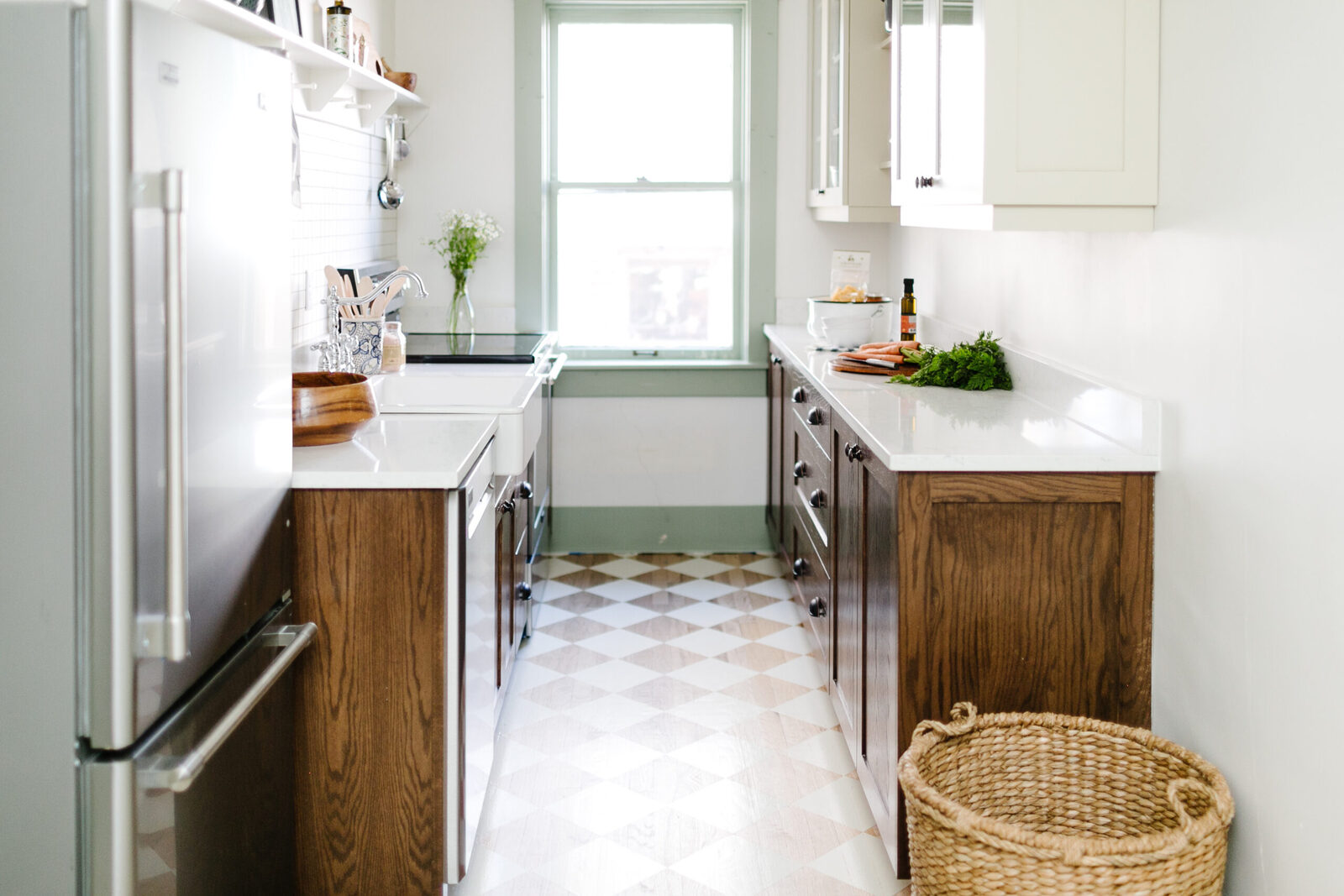 Galley kitchen with white cabinetry, a dark wood island, and a checkered floor in The Laurel Apartments renovation by Forge & Bow