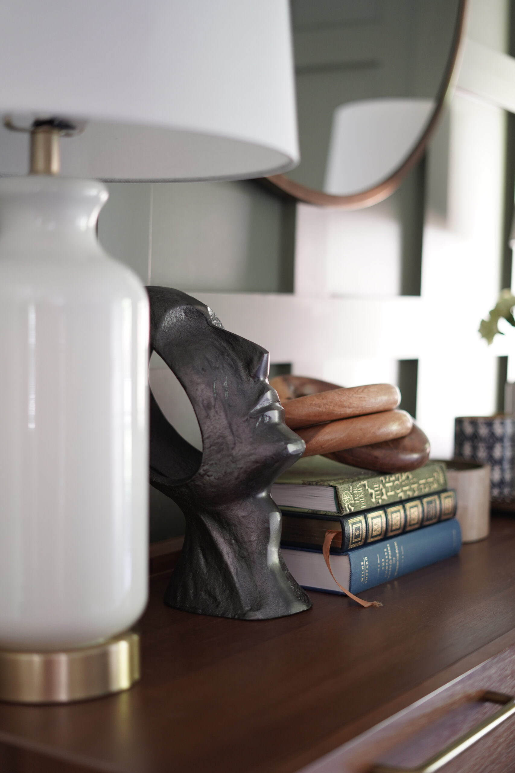 decorative shelving with books, lamps and sculptural face.