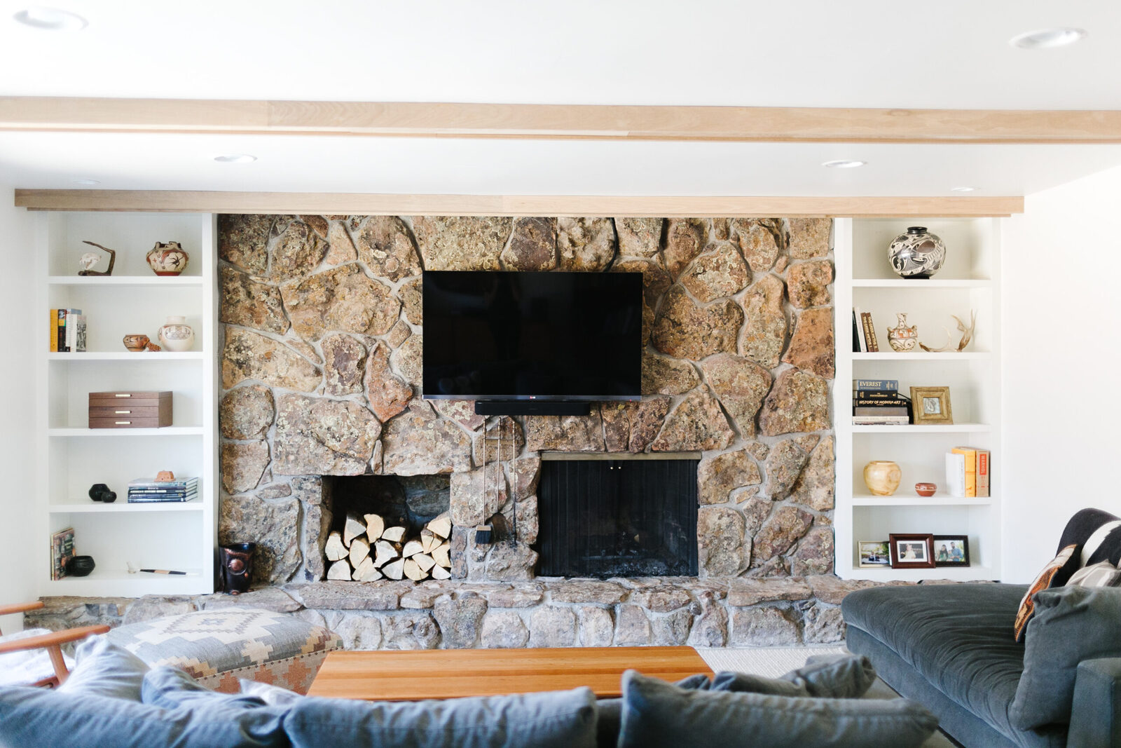 Stone fireplace wall with a mounted TV and matching built-ins in The Teakwood Dwelling renovation by Forge & Bow