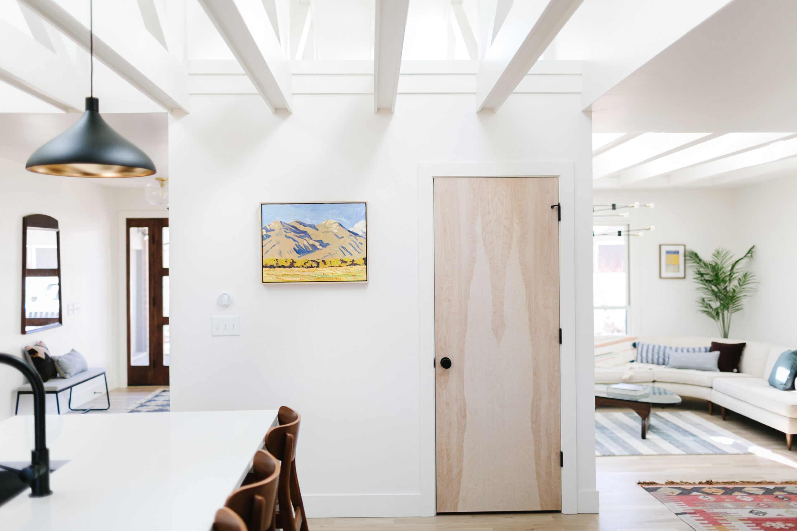 Entry with a black pendant light and wood door opening to the living room in The Teakwood Dwelling renovation by Forge & Bow