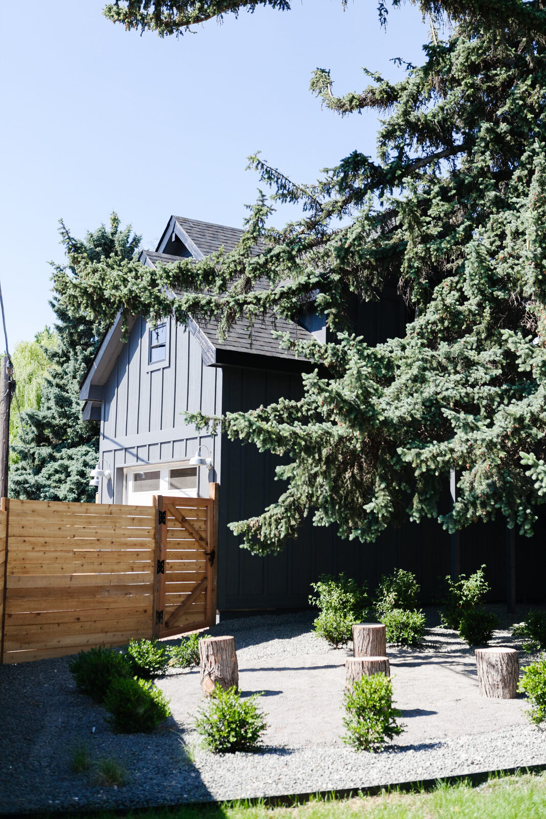 Exterior of the dark board-and-batten cottage surrounded by evergreen trees in The Circle Residence renovation by Forge & Bow