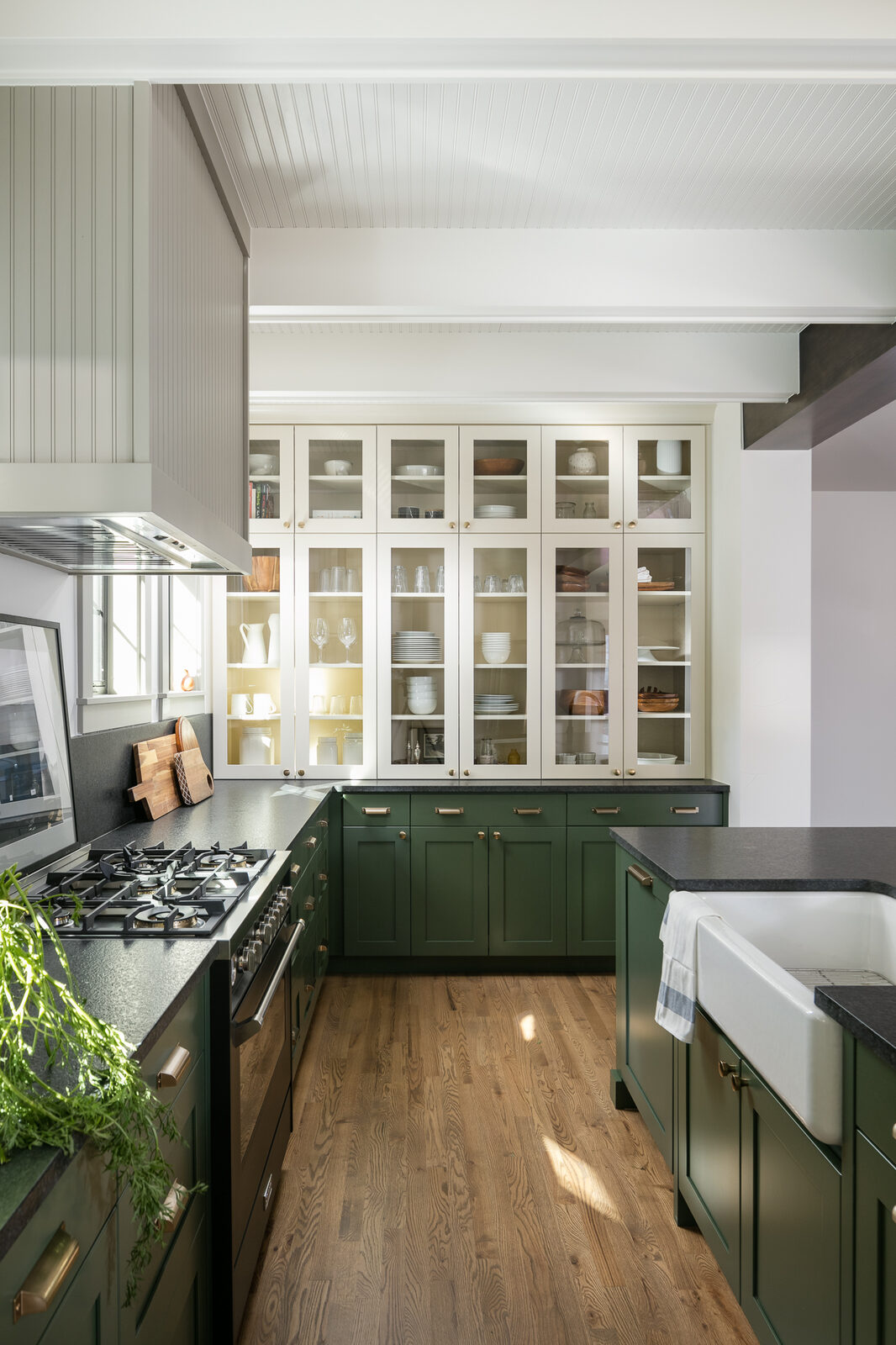 Kitchen with dark green cabinetry, glass-front uppers, and a farmhouse sink in The Mulberry House renovation by Forge & Bow