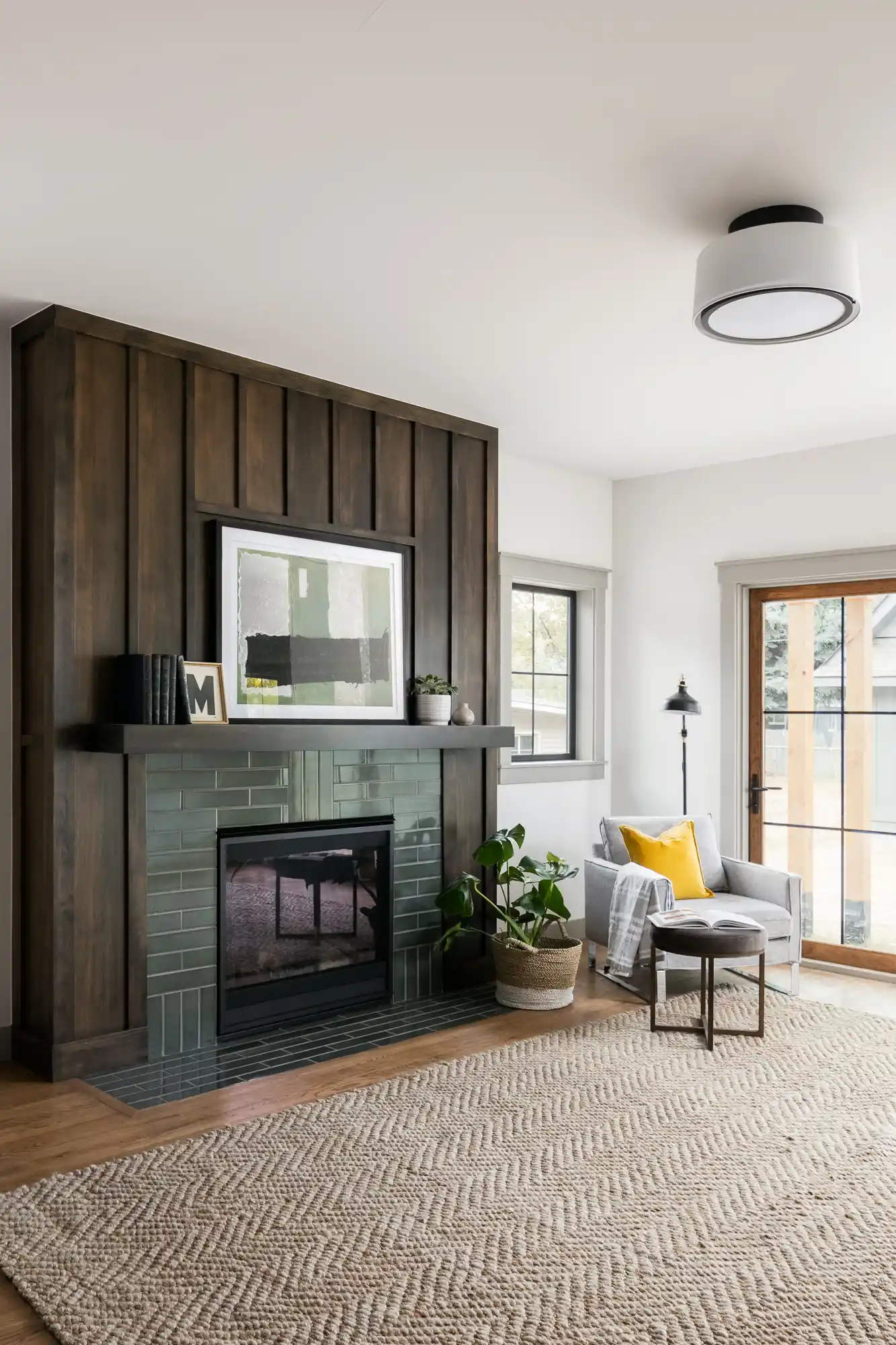 Living room with a dark wood-paneled fireplace wall and green tile surround in The Mulberry House renovation by Forge & Bow