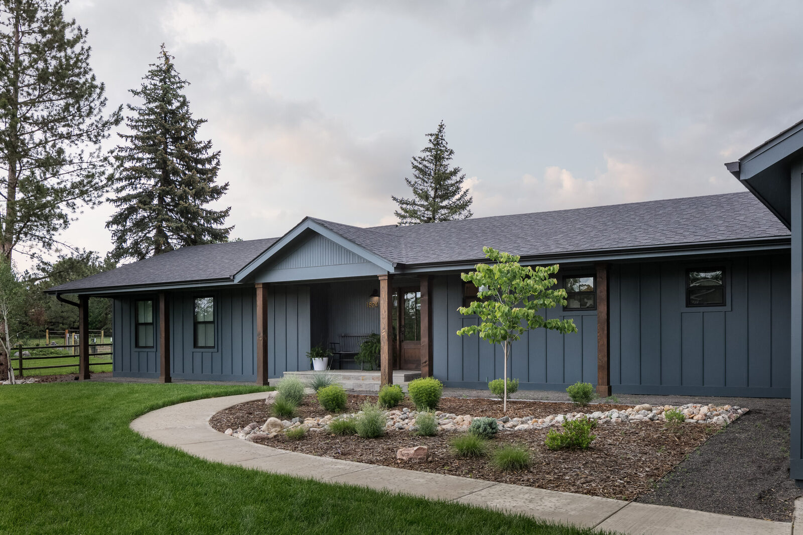 Exterior of the single-story ranch home with dark siding and a standing seam roof in The Marlene Residence renovation by Forge & Bow