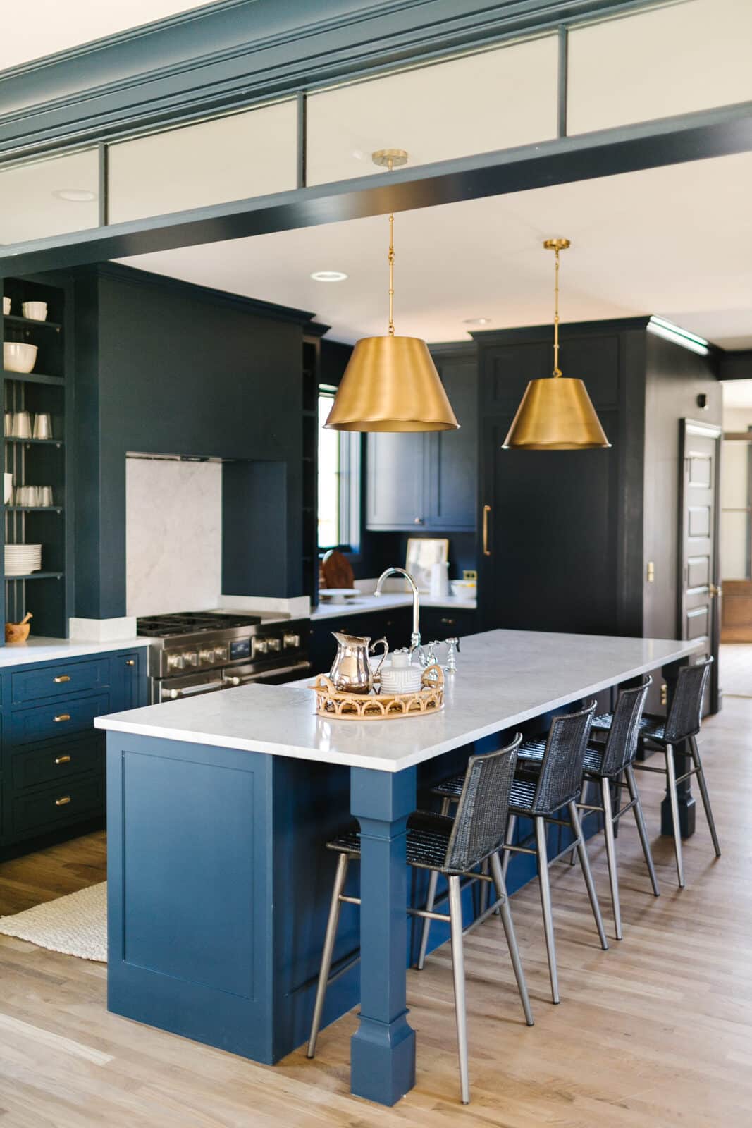 Kitchen island with navy blue cabinetry and brass pendant lights in a Forge & Bow renovation