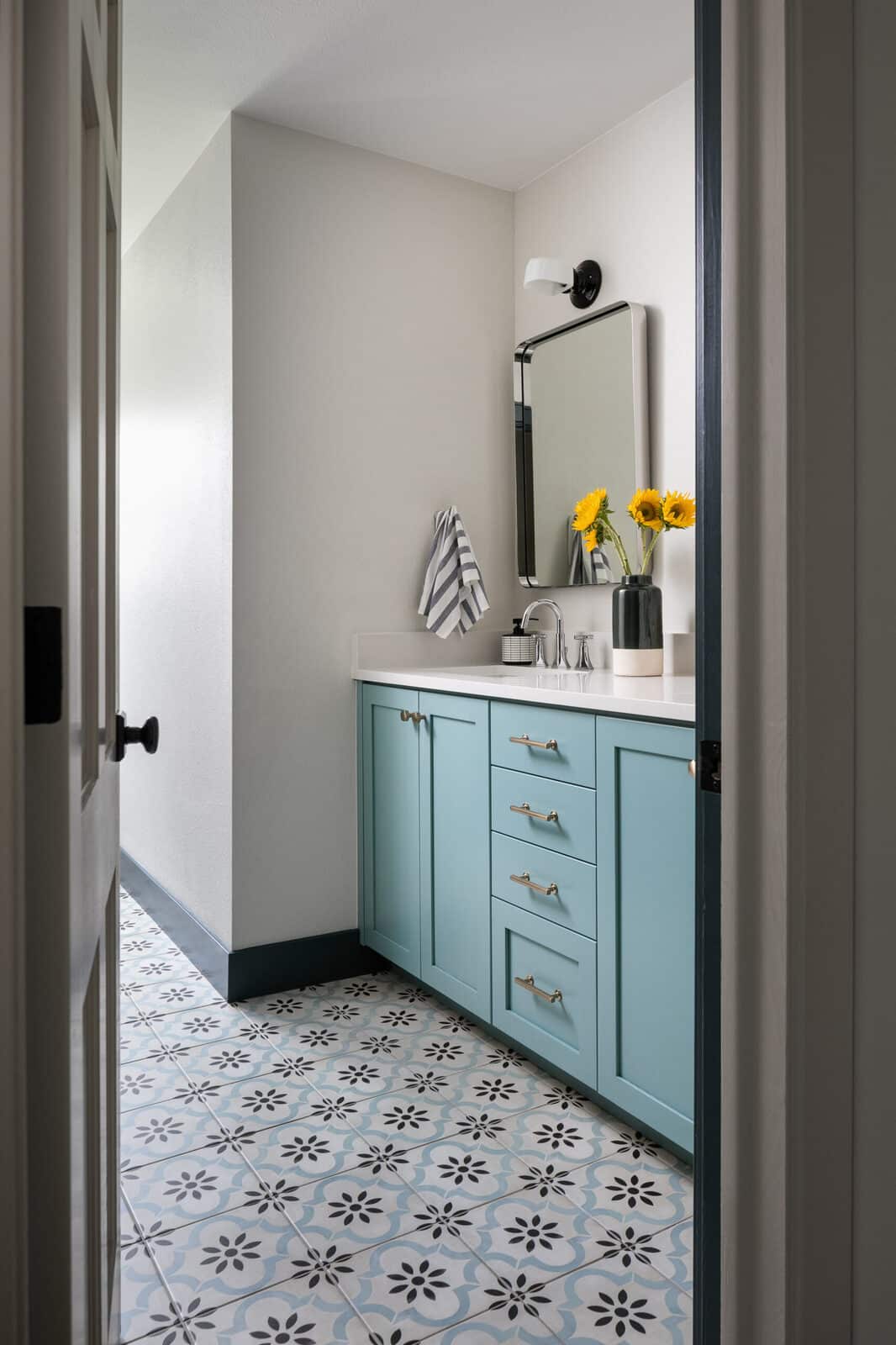 Guest bathroom with a light blue vanity and patterned tile floor in the Seminole renovation by Forge & Bow