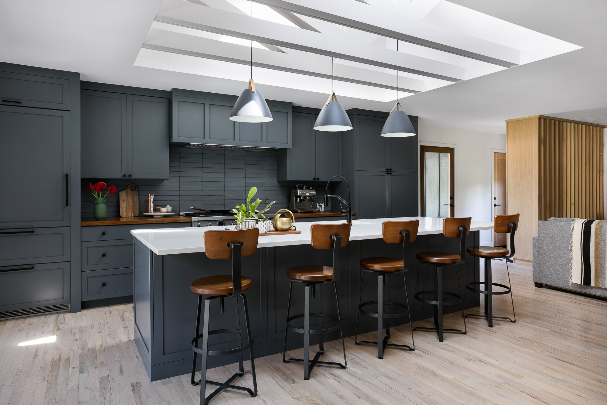Kitchen with charcoal cabinetry and a white waterfall island counter in the Stover renovation by Forge & Bow