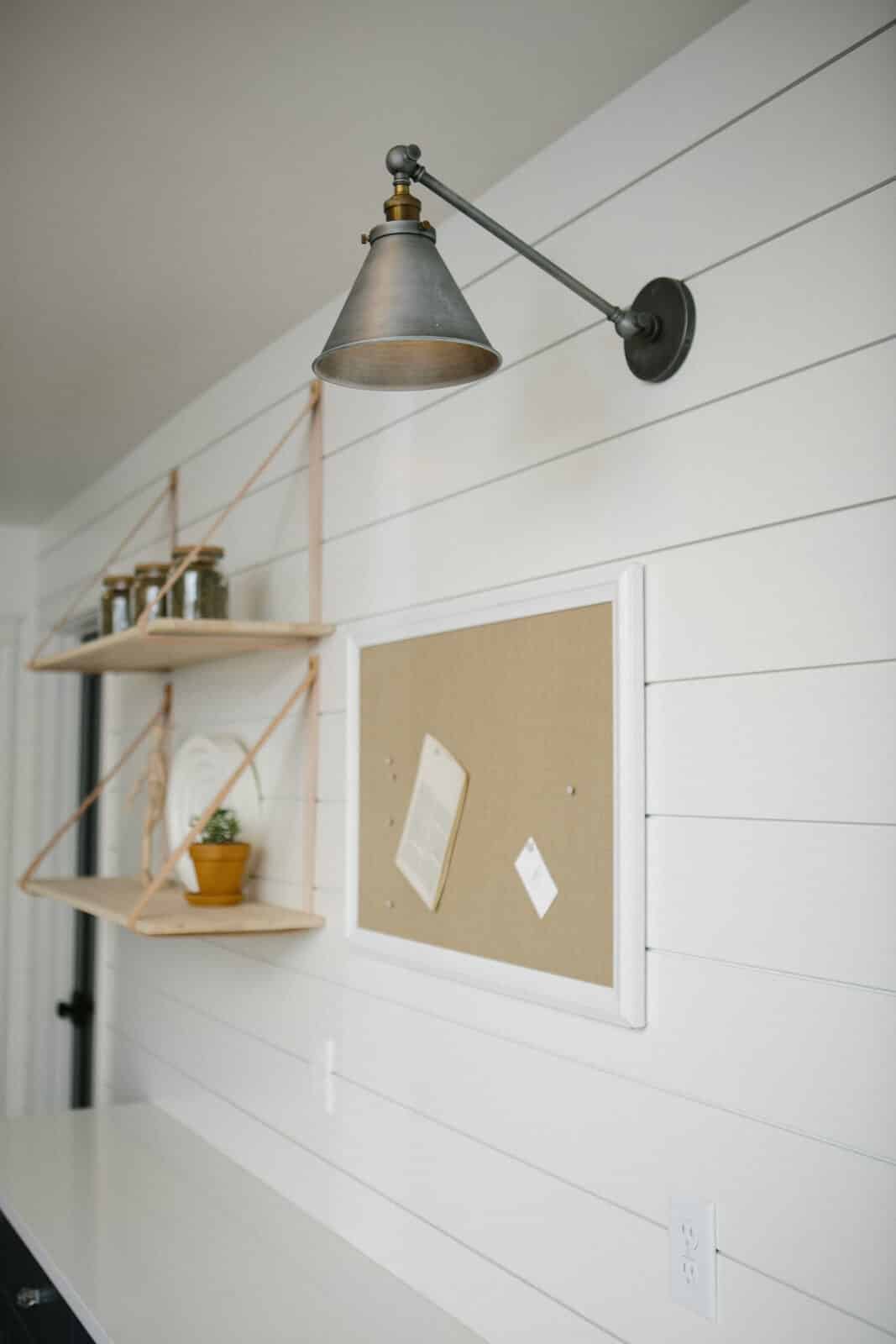Home office nook with a wall-mounted task lamp and hanging wood shelf in The Robertson House renovation by Forge & Bow