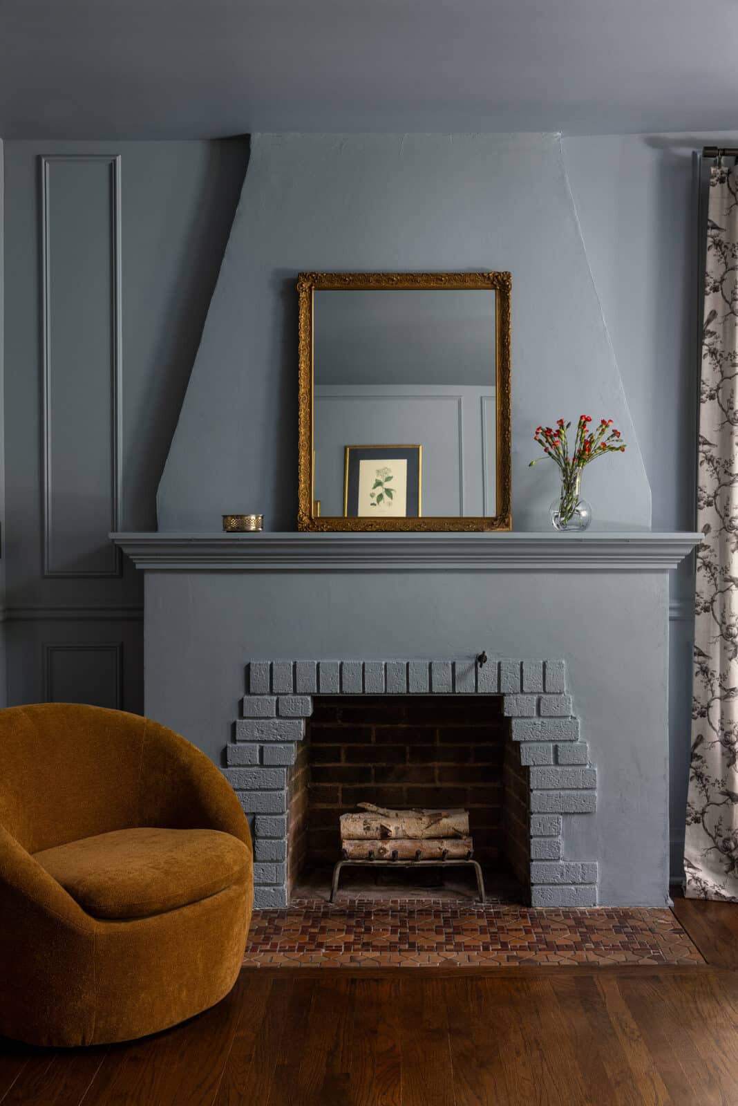 Painted brick fireplace with a gold mirror in The Remington Residence living room renovation by Forge & Bow